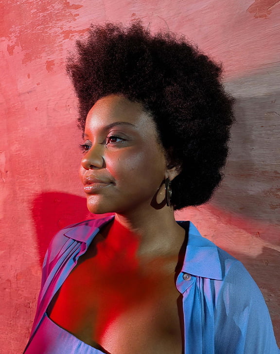 Lifestyle image of female against a wall in red lighting.